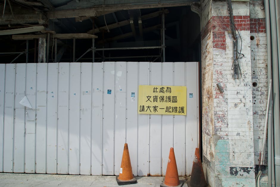Abandoned building site with a warning sign and orange cones.