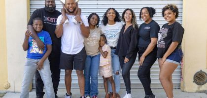 A joyful diverse family group posing together in front of a garage door, showcasing unity and happiness.