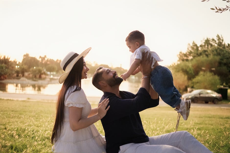 A joyful family moment with parents and child in a sunny park setting.