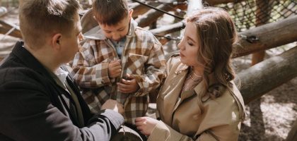 Parents and child sharing moments together at a sunny forest playground.