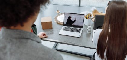 Two colleagues engaging in a remote online meeting at a desk with a laptop.