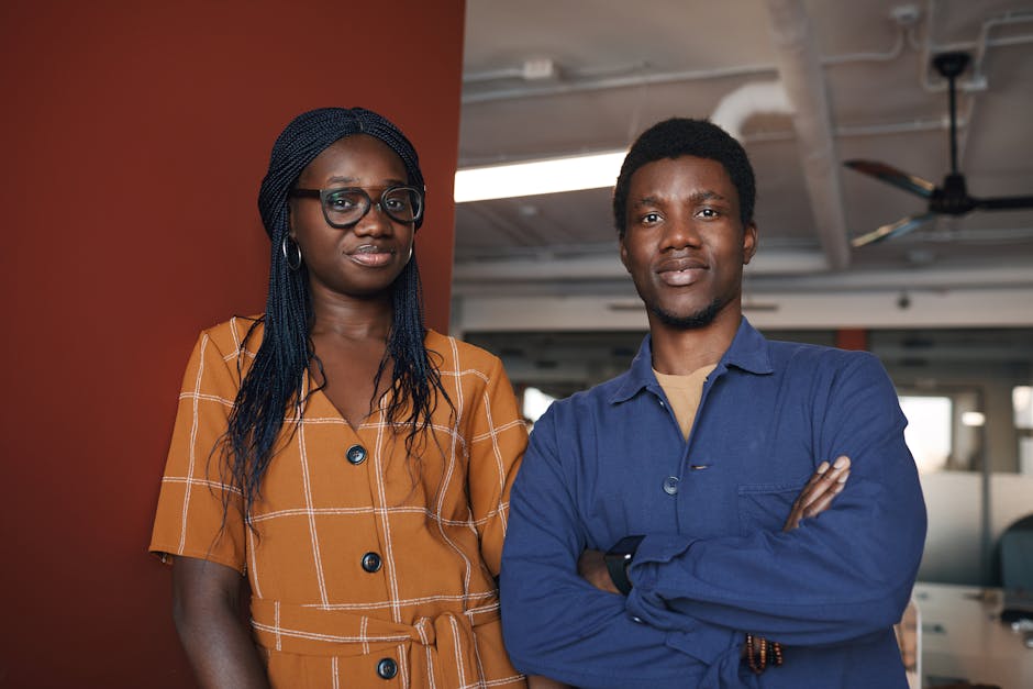 Two confident professionals posing in a contemporary office environment, exuding teamwork and success.