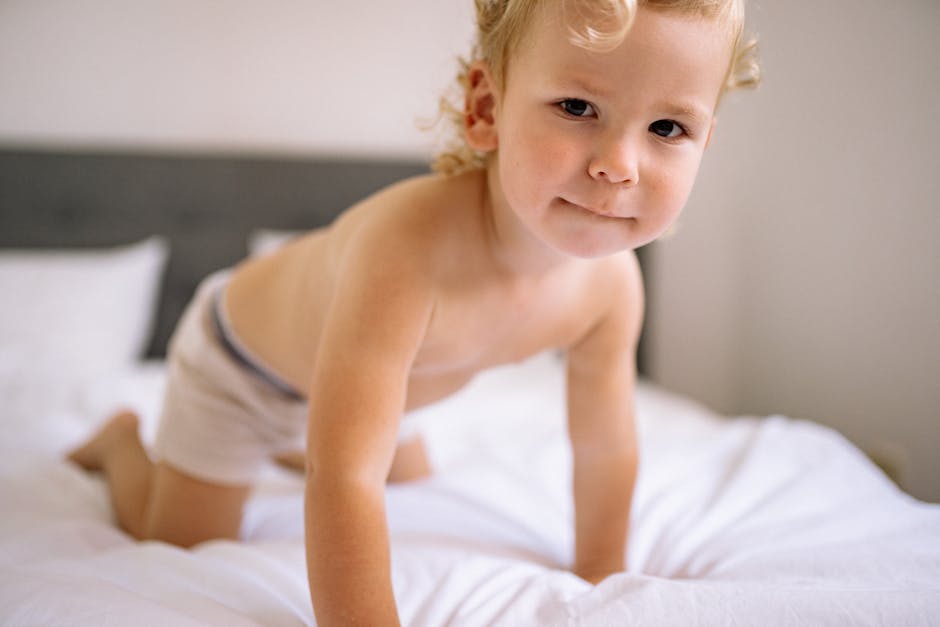 A young child playfully kneeling on a bed in a bright bedroom.